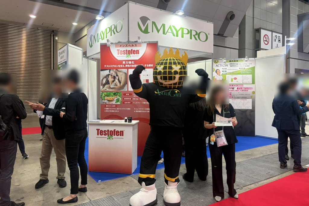 展示会の出展ブースで力こぶのポーズをとる着ぐるみ